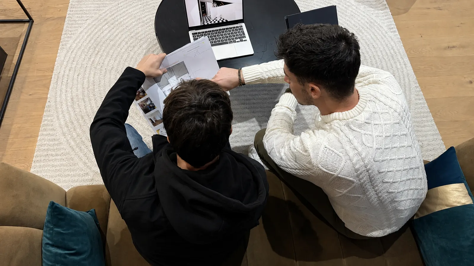 Séance de travail vue de dessus : deux ordinateurs portables et un téléphone sur une grande table en bois.